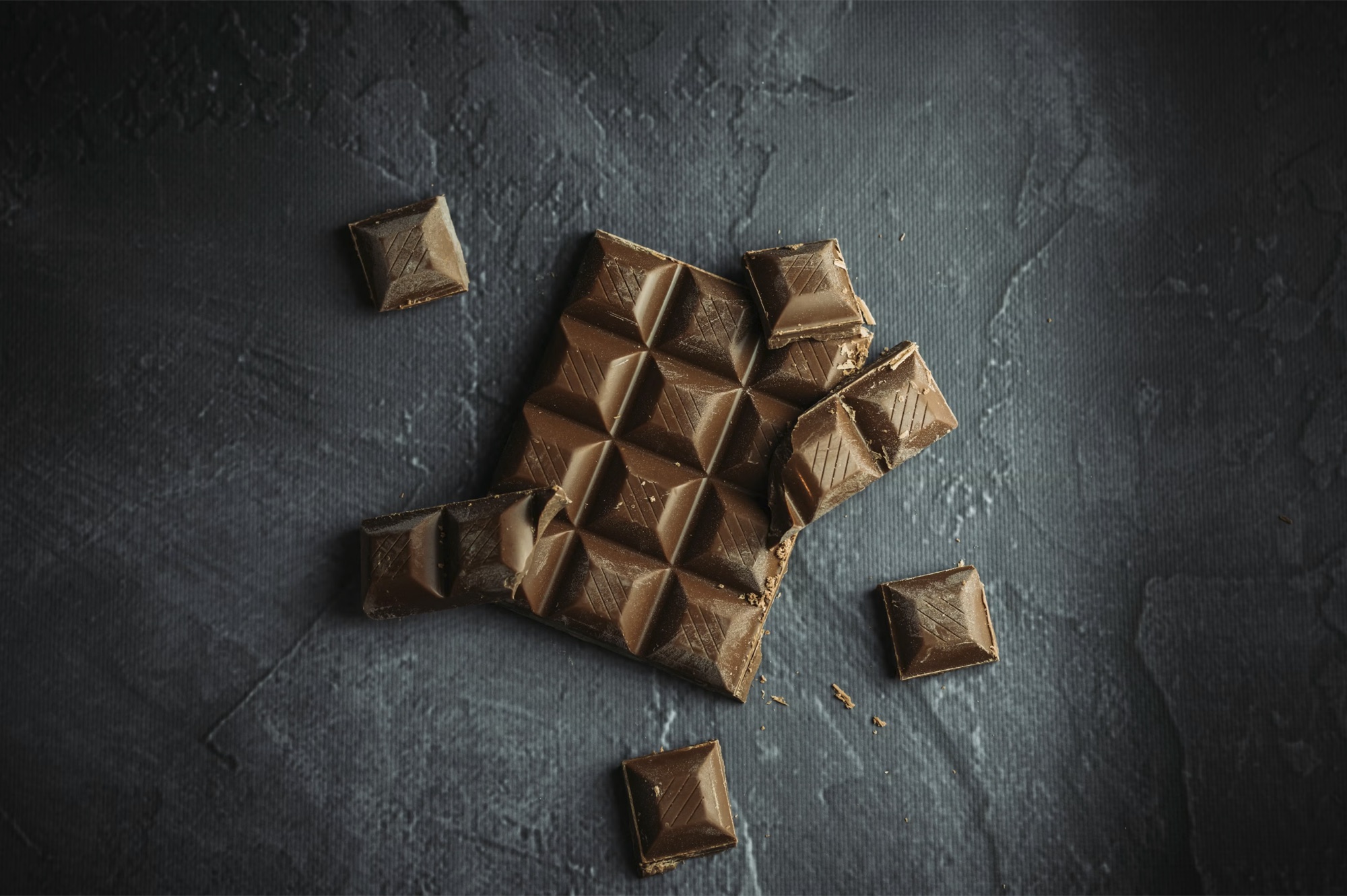 Een chocoladereep waarvan enkele stukken zijn afgebroken en verspreid liggen, als beeld voor een aandelensplitsing: hetzelfde geheel, verdeeld in meer en kleinere stukken.